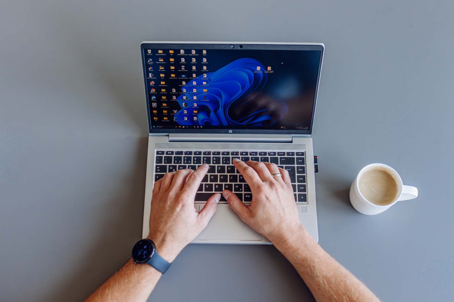 Laptop von oben, Hände tippen und eine Tasse Kaffee