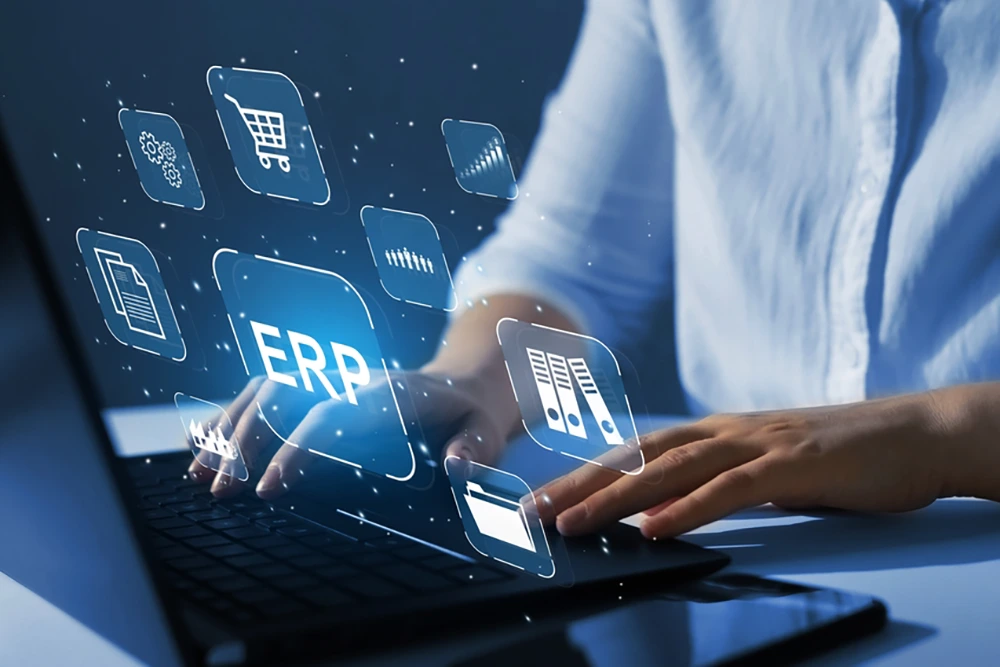 Hände tippen auf einem Laptop, über dem digitale Symbole für Einkaufswagen, Dokumente, Aktenordner und Zahnräder schweben. Das zentrale Symbol zeigt „ERP“ für Unternehmenssoftware.